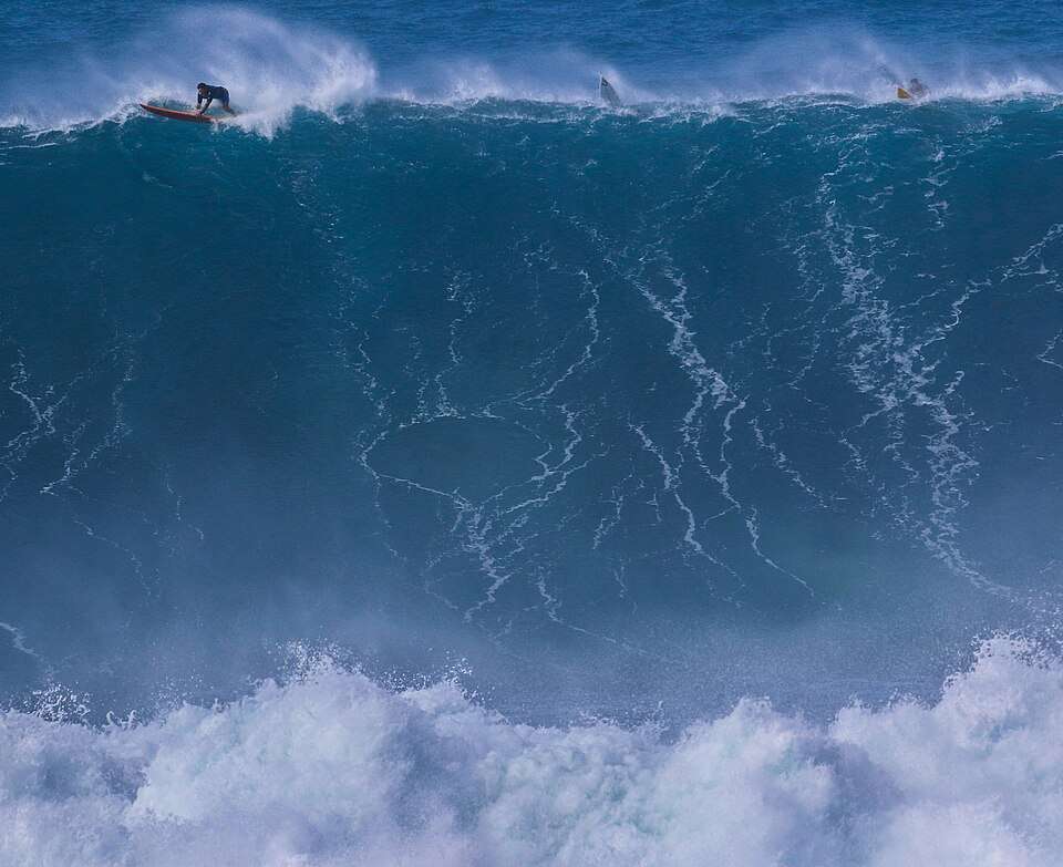 A surfer dropping into a winter wave at Waimea Bay